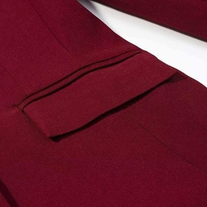 Détail d'un blazer rouge foncé montrant la poche plaquée et la texture tissée
