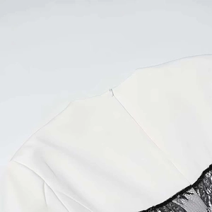 Detail view of invisible zipper and black lace stitching on the white dress neckline