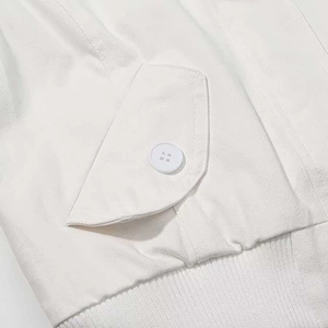 Detailed macro shot of white jacket with button flap pocket and ribbed knitted hemline