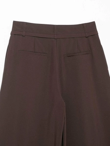 Detailed view of dark brown high-waisted trousers with rear pockets and belt loops