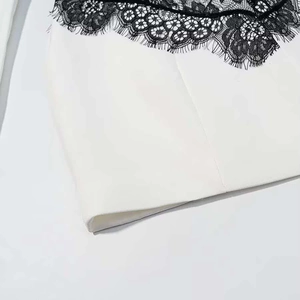 Macro shot of elegant white fabric with black floral lace stitching and delicate trim
