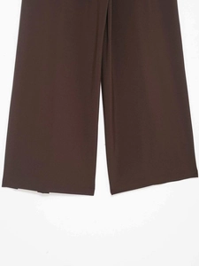 Detail of loose wide-leg dark brown trousers hem featuring fine plain weave fabric texture