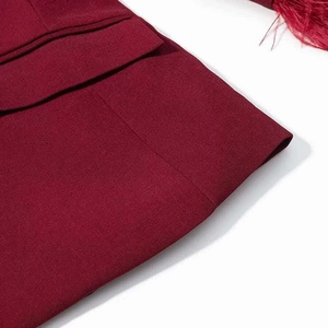 Gros plan de la poche blazer bordeaux avec texture sergé et bordure en plumes