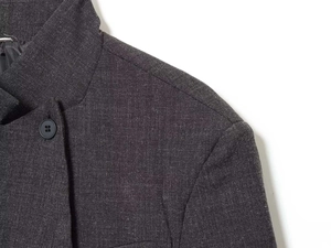 Detailed close-up of dark grey wool blend blazer fabric texture and black matte button