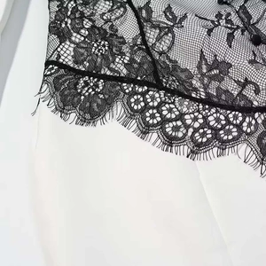 Detail shot of delicate black floral lace stitching with eyelash trim on white fabric