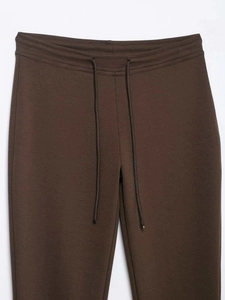 Detail of high waist elastic waistband with adjustable drawstring on dark brown flared pants