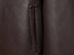 Close-up of double-stitched pocket detail on dark brown vintage faux leather jacket