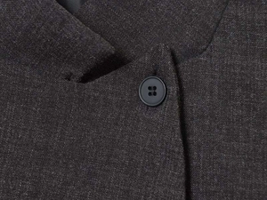 Detailed close-up of dark grey blazer collar with classic black round button