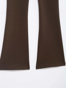 Detailed view of wide flared hem and clean stitched edge on coffee brown trousers