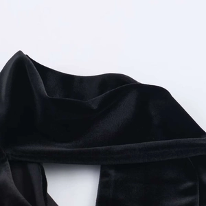 Dettaglio dell'elegante abito in velluto nero che mostra la trama del tessuto e il collo