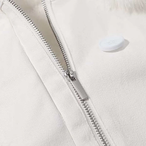 Close-up of silver metal zipper, button and faux fur collar on white hooded jacket