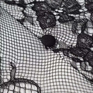 Close-up of black floral lace texture with a fabric-covered button on a contrast lining