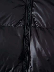 Detail der schwarzen glänzenden Pufferjacke mit Harzreißverschluss und Steppmuster