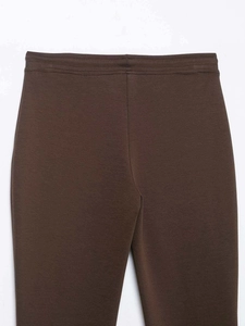 Detail of high-waist elastic waistband and stitching on dark brown flared trousers