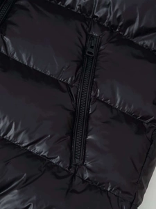 Detail von glänzend schwarzem Steppstoff mit Reißverschluss an einer Winter-Steppjacke
