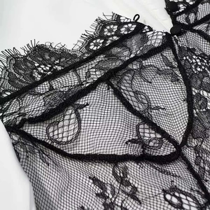 Detail of white dress featuring intricate black floral lace and matching cloth buttons