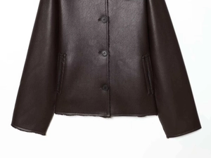 Close-up of deep brown leather jacket featuring button closure and textured pocket details