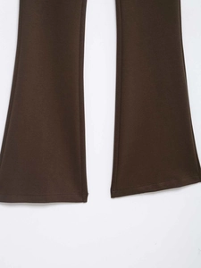 Detailed view of dark brown flared trousers leg hem with premium knitted texture