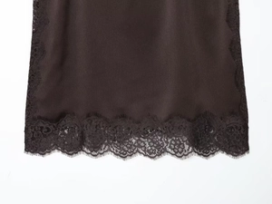 Detail of dark brown satin hem featuring intricate eyelash lace and silky fabric texture