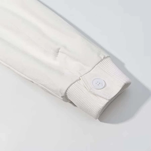Detailed close-up of ribbed cuffs and button stitching on white hooded jacket sleeves