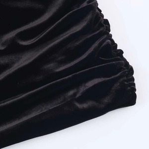 Detail of ruched black velvet fabric texture on a short dress with shoulder pads