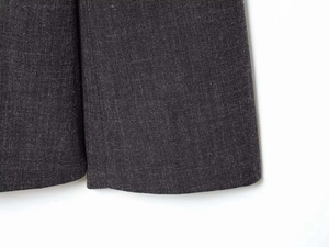 Detailed close-up of dark grey wool blend blazer fabric texture and hem stitching quality