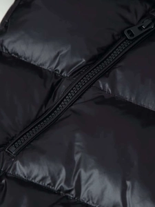Nahaufnahme der schwarzen, glänzenden Steppjacke mit hochwertigem Reißverschluss und Füllung