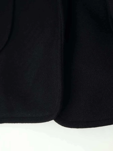 Detailed close-up of a black wool coat hem showing high-quality stitching and fabric texture