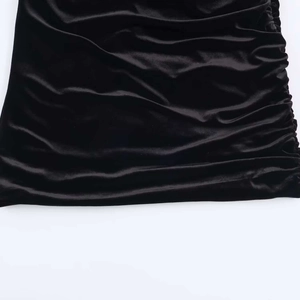 Detail of black velvet dress with side ruched texture and soft light-reflecting sheen