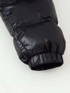 Detailaufnahme der glänzenden schwarzen Steppjacke mit elastischem Bündchen und Nylonstoff