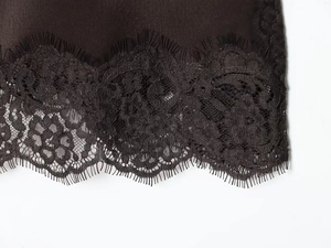 Detail of delicate black eyelash lace trim on glossy silk camisole top for women