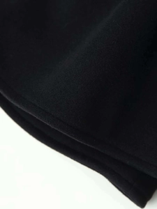 Detailed close-up of thick black wool fabric texture with fine edge stitching and soft finish