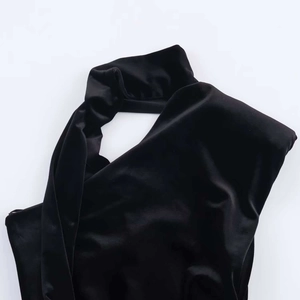 Dettaglio dell'elegante abito in velluto nero con scollo a sciarpa e trama del tessuto morbido