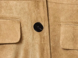 Detailed close-up of camel suede jacket texture with resin button and flap pocket