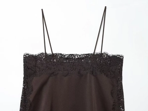 Detail of black satin camisole featuring delicate eyelash lace trim and thin straps