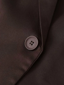 Detailed macro view of dark coffee blazer featuring a four-hole resin button and matte fabric