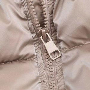Close-up of metallic champagne puffer jacket featuring a durable metal zipper detail