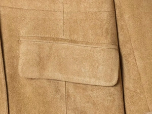 Detailed macro shot of tan suede jacket featuring a rectangular pocket and reinforced stitching
