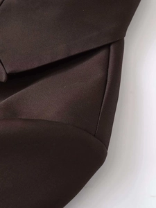 Close-up of dark brown woven fabric and tailoring details on a loose-fit blazer