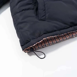 Detailed macro view of quilted jacket hem featuring brown plaid lining and adjustable drawstring