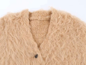 Detailed close-up of soft camel fluffy knit sweater with V-neck and black button