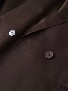 Detail view of dark brown double-breasted blazer showing lapels and contrast buttons