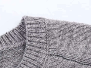 Close-up of the seam detailing and neckline on a grey wool blend knit sweater