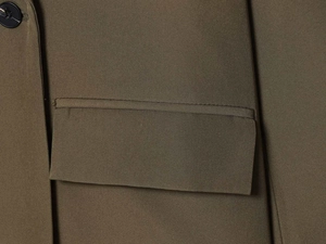 Detailansicht des olivgrünen Blazers mit Pattentasche und feiner Naht auf dem Webstoff