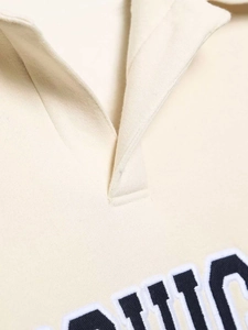 Détail d'un sweat polo beige avec broderie de lettres rétro de style universitaire US