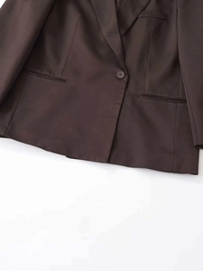 Detailed macro view of dark brown twill fabric and flap pocket on a women suit jacket