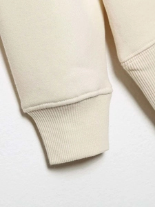 Gros plan détaillé du poignet côtelé élastique sur un sweat en maille blanc crème
