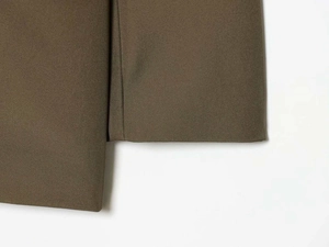 Detailansicht der dunkeloliven Stofftextur und präzisen Nähte am Ärmelabschluss der Jacke