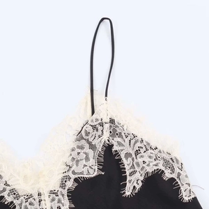 Detailed close-up of cream floral eyelash lace trim on a black satin camisole top