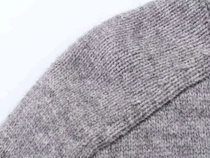 Macro detail of soft grey knit sweater showing fine wool texture and quality stitching